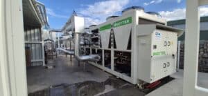 Chiller industriel KEYTER blanc et vert avec logo C2R, raccordé à une tuyauterie isolée en extérieur. Installation de froid commercial sous ciel nuageux.
